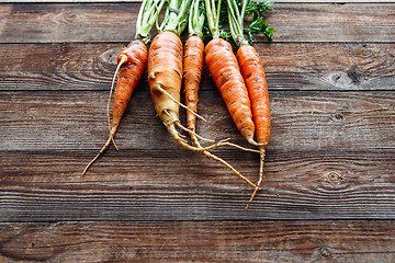 Image showing Raw carrot with green leaves on wooden background