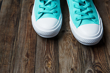 Image showing Blue sneakers on empty Brown parquet