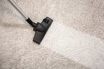 Image showing Vacuum cleaner vacuuming dusty carpet