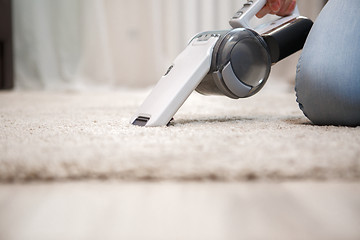 Image showing Process of cleaning carpet with help portable vacuum cleaner