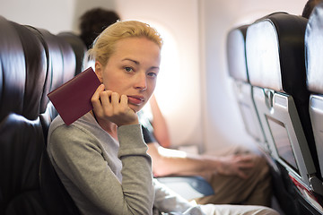 Image showing Woman traveling by plae holding passport in her hand.