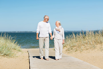 Image showing happy senior couple holding hands on summer beach