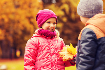 Image showing little boy giving autumn maple leaves to girl