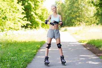 Image showing happy young woman in rollerblades riding outdoors