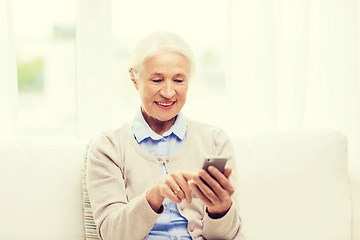 Image showing senior woman with smartphone texting at home