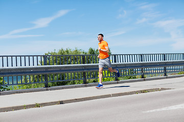 Image showing smiling young man running at summer seaside