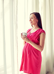 Image showing happy pregnant woman with cup drinking at home