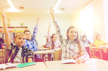 Image showing group of school kids raising hands in classroom