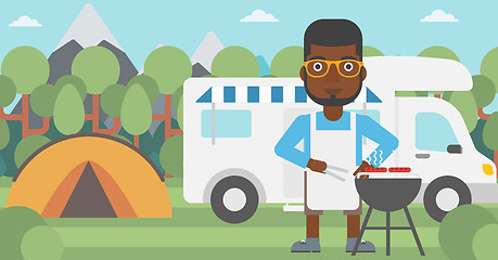 Image showing Man having barbecue in front of camper van.