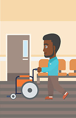 Image showing Man pushing wheelchair.