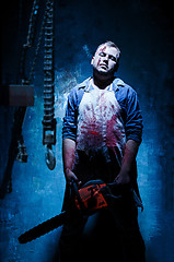 Image showing Bloody Halloween theme: crazy killer as butcher with electric saw