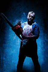 Image showing Bloody Halloween theme: crazy killer as butcher with electric saw