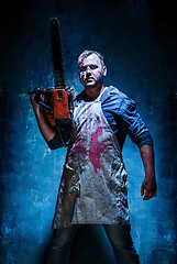 Image showing Bloody Halloween theme: crazy killer as butcher with electric saw