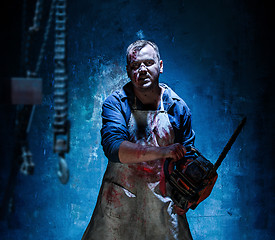 Image showing Bloody Halloween theme: crazy killer as butcher with electric saw