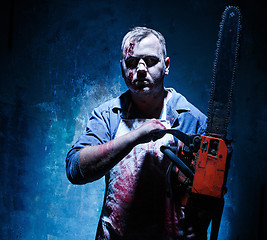 Image showing Bloody Halloween theme: crazy killer as butcher with electric saw