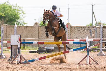 Image showing Volgograd, Russia - June 19, 2016: Athletes train a horse doing a jump through the barrier