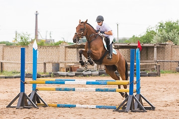 Image showing Volgograd, Russia - June 19, 2016: The athlete performs a jump on a horse through the barrier on the jumping competition