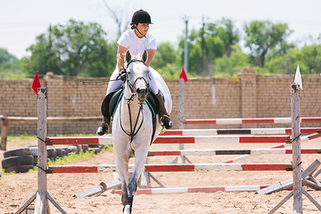 Image showing Volgograd, Russia - June 19, 2016: The sportswoman on a horse has successfully completed the jump across the barrier