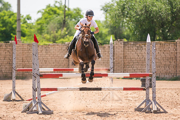 Image showing Volgograd, Russia - June 19, 2016: Rider on a horse jumping over the barrier at the jumping competition