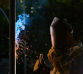 Image showing welder worker welding metal by electrode