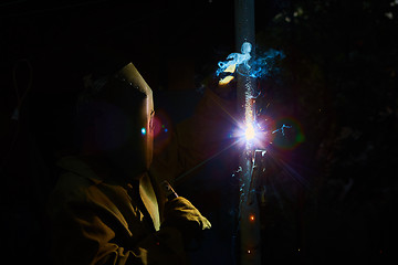 Image showing welder worker welding metal by electrode