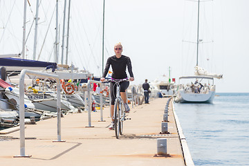 Image showing Young active woman cycling on pier in marina.