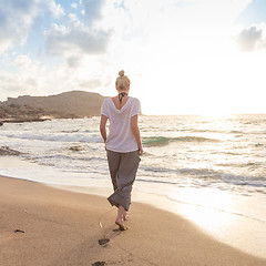 Image showing Woman walking on sand beach at golden hour