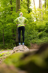 Image showing Woman standing on tree trunk in nature.