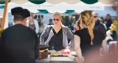 Image showing Woman buying meal at street food festival.