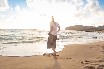 Image showing Woman walking on sand beach at golden hour