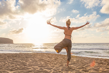 Image showing Woman practicing yoga on sea beach at sunset.