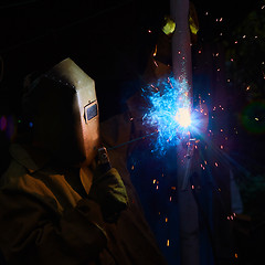 Image showing welder worker welding metal by electrode