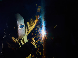 Image showing welder worker welding metal by electrode