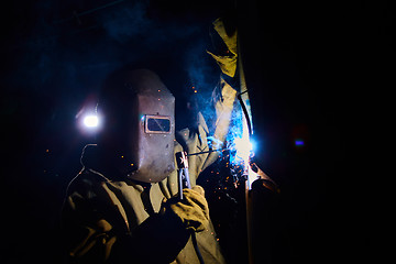 Image showing welder worker welding metal by electrode