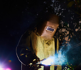 Image showing welder worker welding metal by electrode