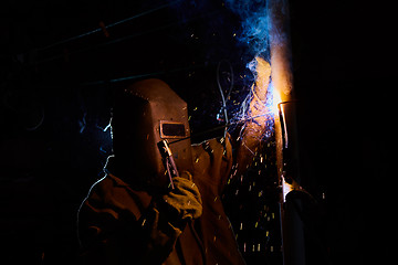 Image showing welder worker welding metal by electrode