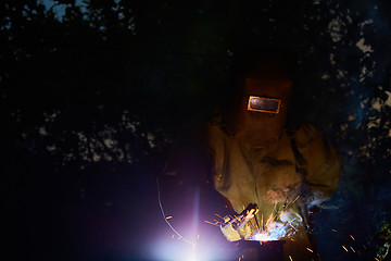 Image showing welder worker welding metal by electrode