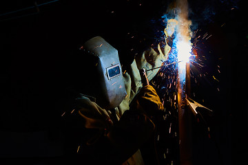 Image showing welder worker welding metal by electrode