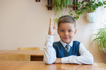 Image showing Happy schoolboy sitting at desk