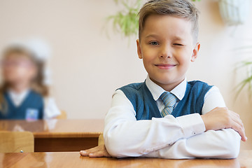 Image showing Happy schoolboy sitting at desk