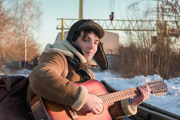 Image showing Guy On Railway Tracks In Winter Playing Guitar