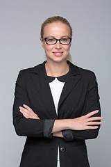 Image showing Business woman standing with arms crossed against gray background..