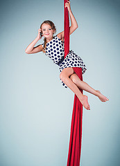 Image showing Graceful gymnast sitting with red fabrics and phone