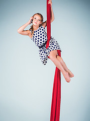 Image showing Graceful gymnast sitting with red fabrics and phone