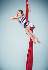 Image showing Graceful gymnast sitting with red fabrics and phone