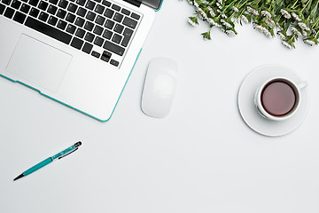 Image showing Office desk table with computer, supplies, flowers and coffee cup.