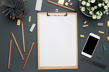 Image showing Office desk table with pencils, supplies, phone and flowers