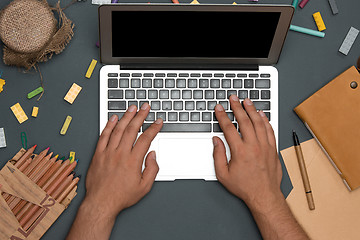 Image showing Office desk table with pencils, supplies, laptop and male hands