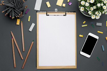 Image showing Office desk table with pencils, supplies, phone and flowers