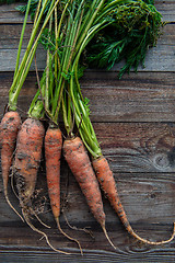 Image showing Bunch of orange carrots fresh with dirt on old rustic wood background
